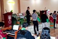 AKP Sonahami Lase menuntun seorang wanita tuna netra untuk menerima bingkisan kasih berupa sembako di Gereja BNKP Jemaat Onozikho pada Minggu, 29 Juni 2025. JOJOR MASIHOL MARITO/BALUSENIAS.COM