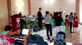 AKP Sonahami Lase menuntun seorang wanita tuna netra untuk menerima bingkisan kasih berupa sembako di Gereja BNKP Jemaat Onozikho pada Minggu, 29 Juni 2025. JOJOR MASIHOL MARITO/BALUSENIAS.COM