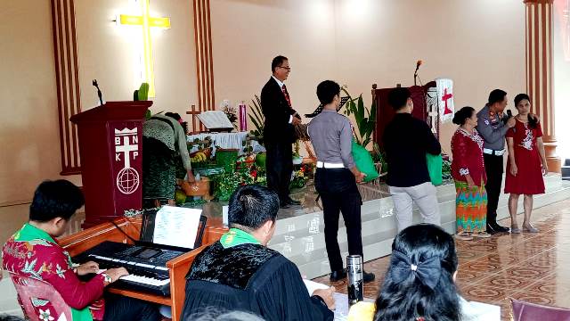 AKP Sonahami Lase menuntun seorang wanita tuna netra untuk menerima bingkisan kasih berupa sembako di Gereja BNKP Jemaat Onozikho pada Minggu, 29 Juni 2025. JOJOR MASIHOL MARITO/BALUSENIAS.COM